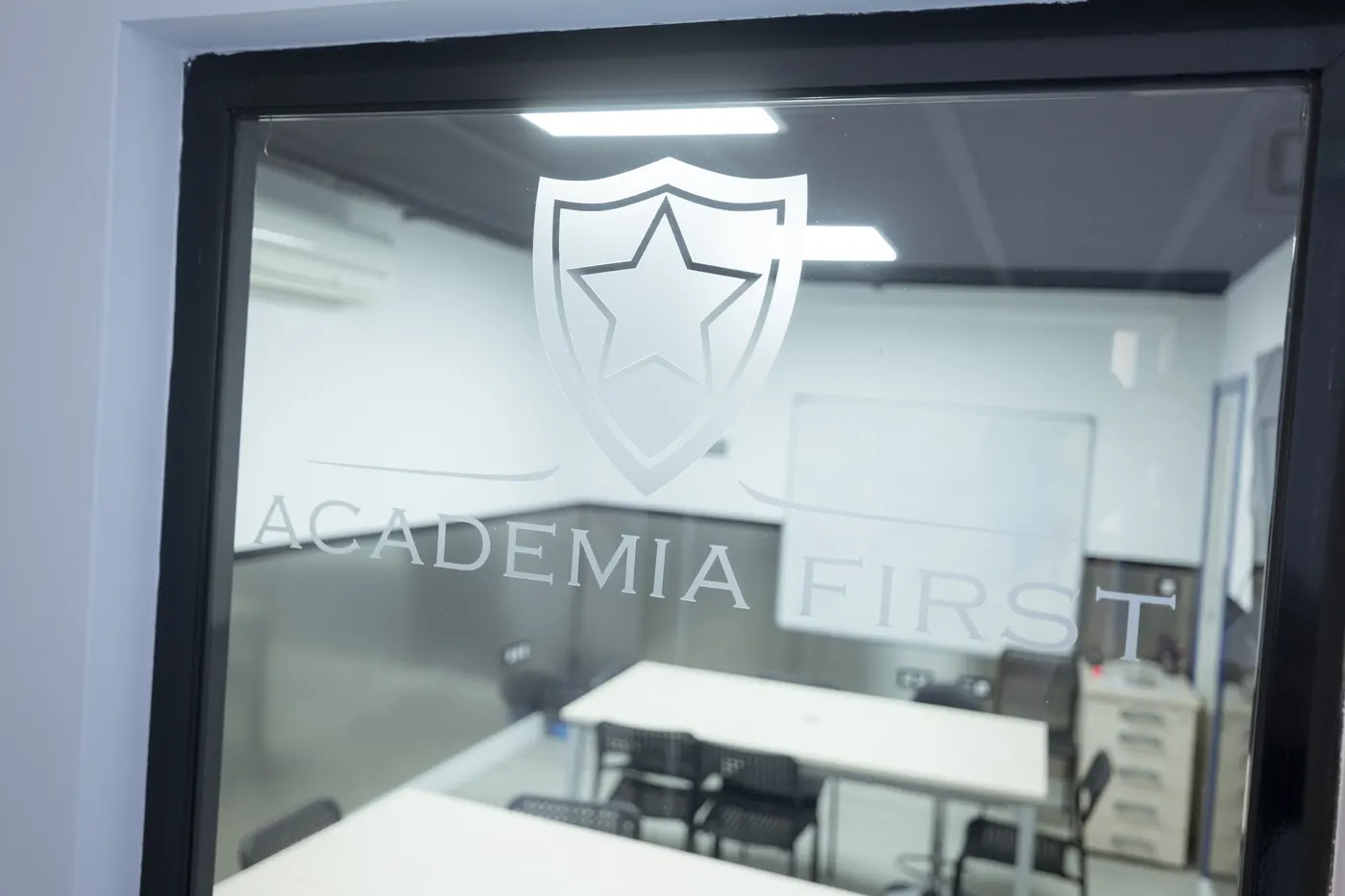 Escudo de Academia First grabado en el cristal de un aula.