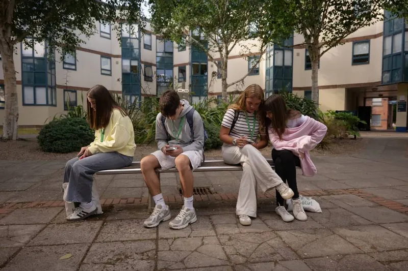 Alumnos del campamento descansando en un banco del campus.
