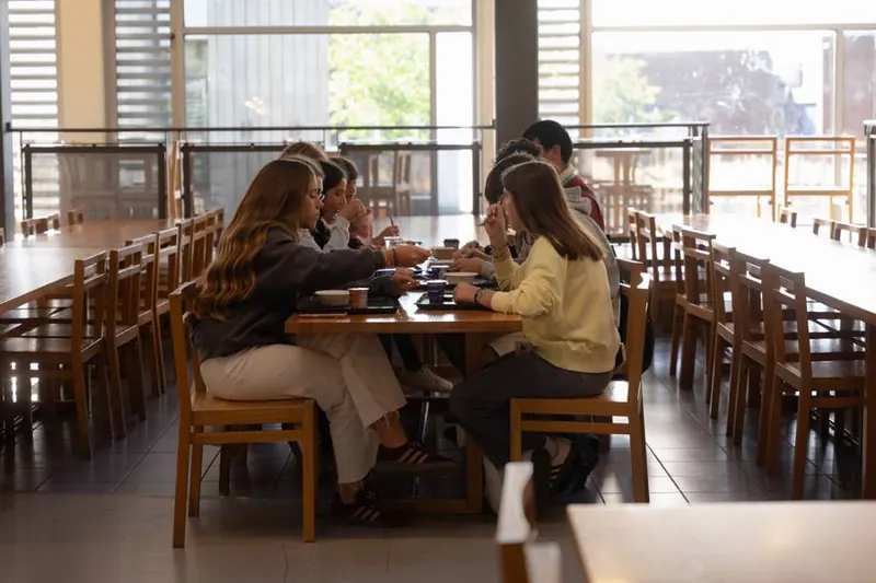 Alumnos del campamento comiendo juntos en el comedor.